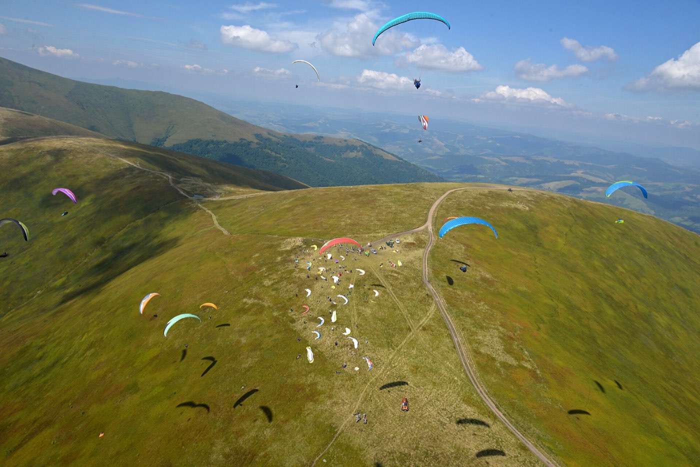 A paraglider in flight over mountains