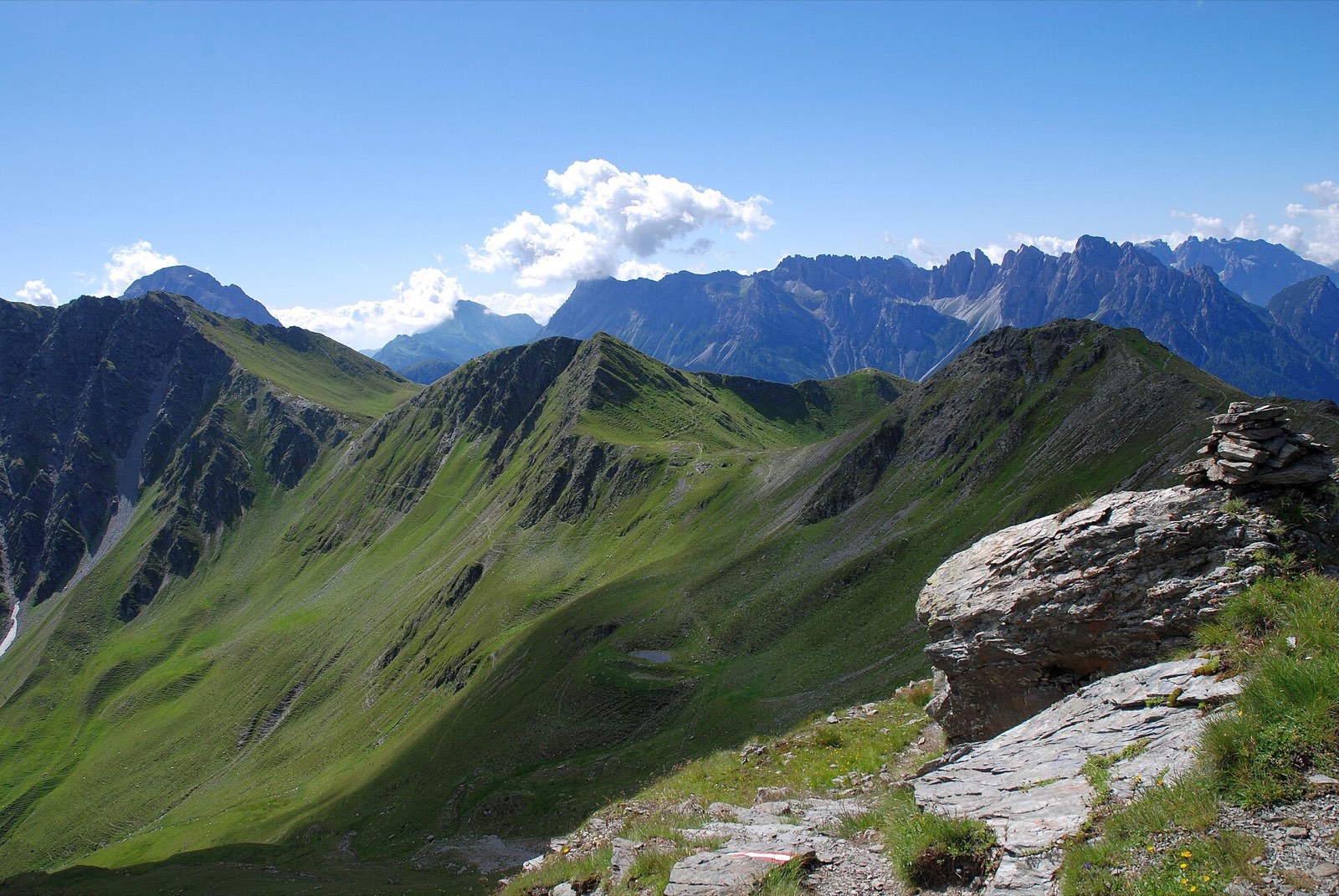 A hiking trail winding along a green alpine ridge